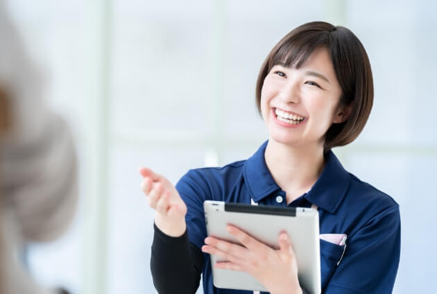 タブレットを持った女性介護士が、明るい笑顔で利用者に対応している様子